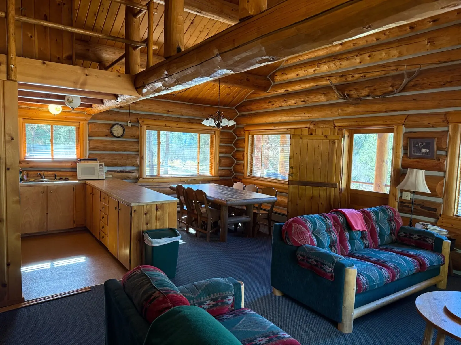 Inside the Ponderosa: open kitchen, dining table and living room under a high log ceiling