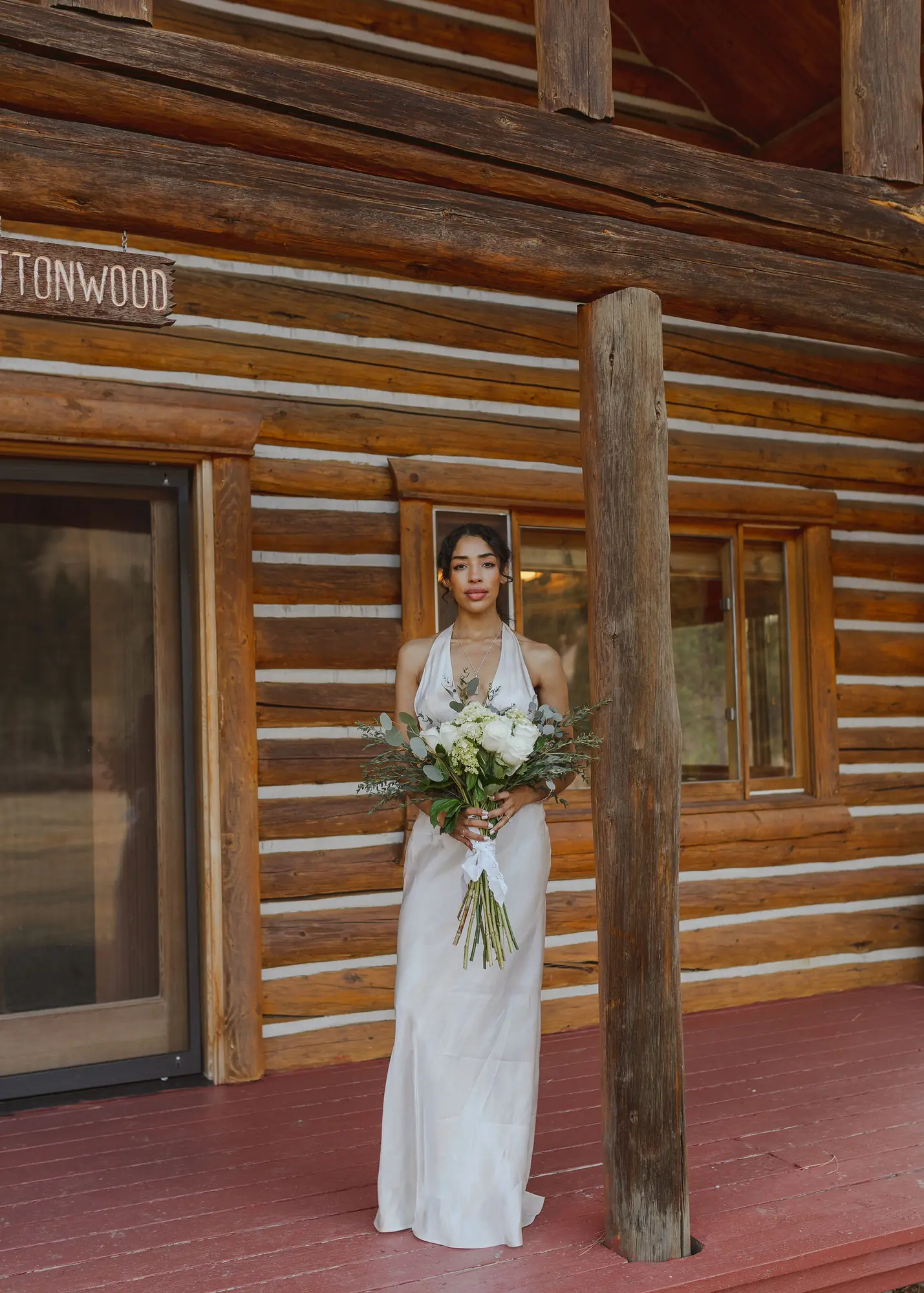A bride on the porch of the Cottonwood cabin at Alta Ranch
