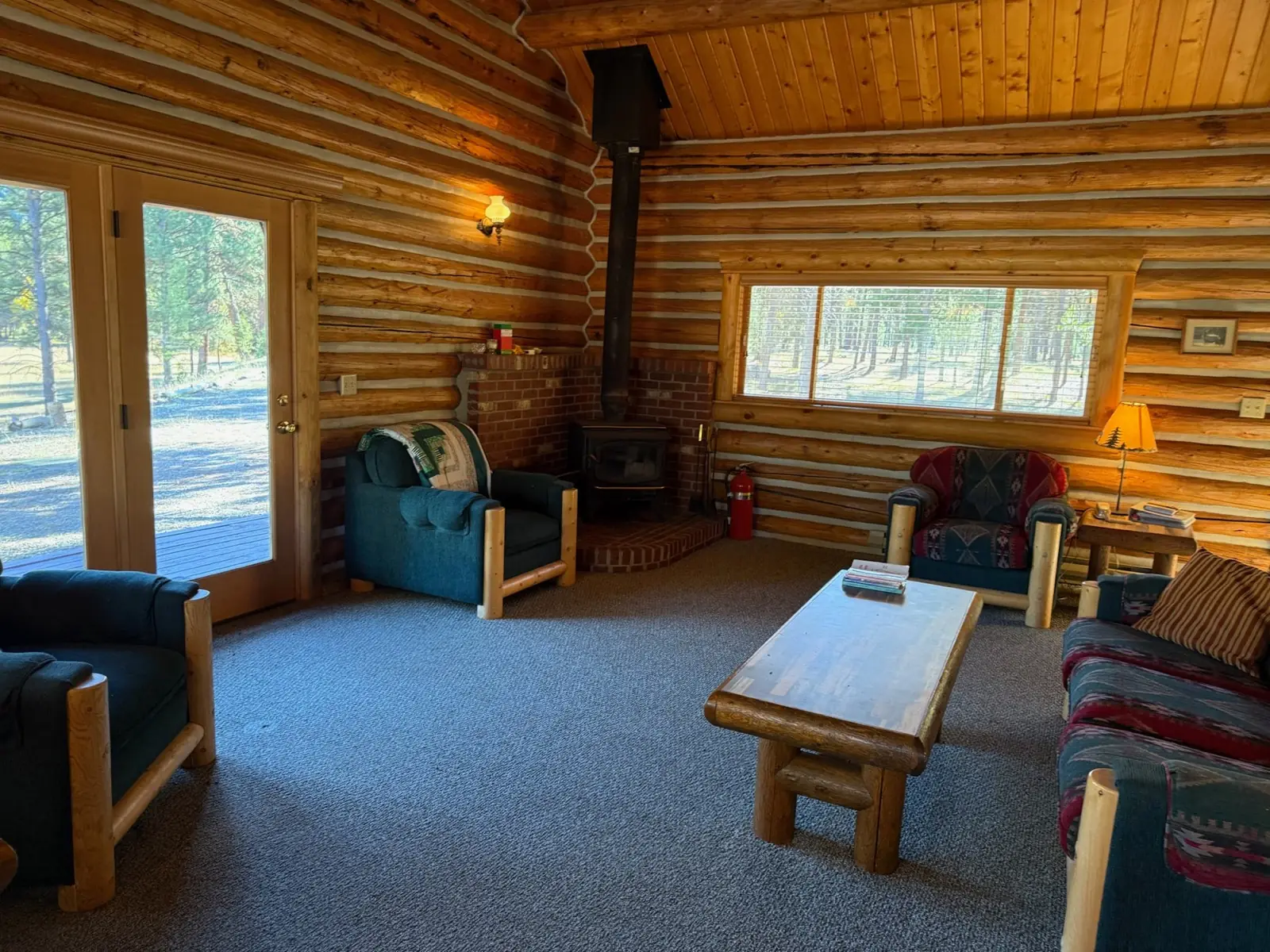 Inside the Cottonwood: warm wood living area with a wood stove and glass doors