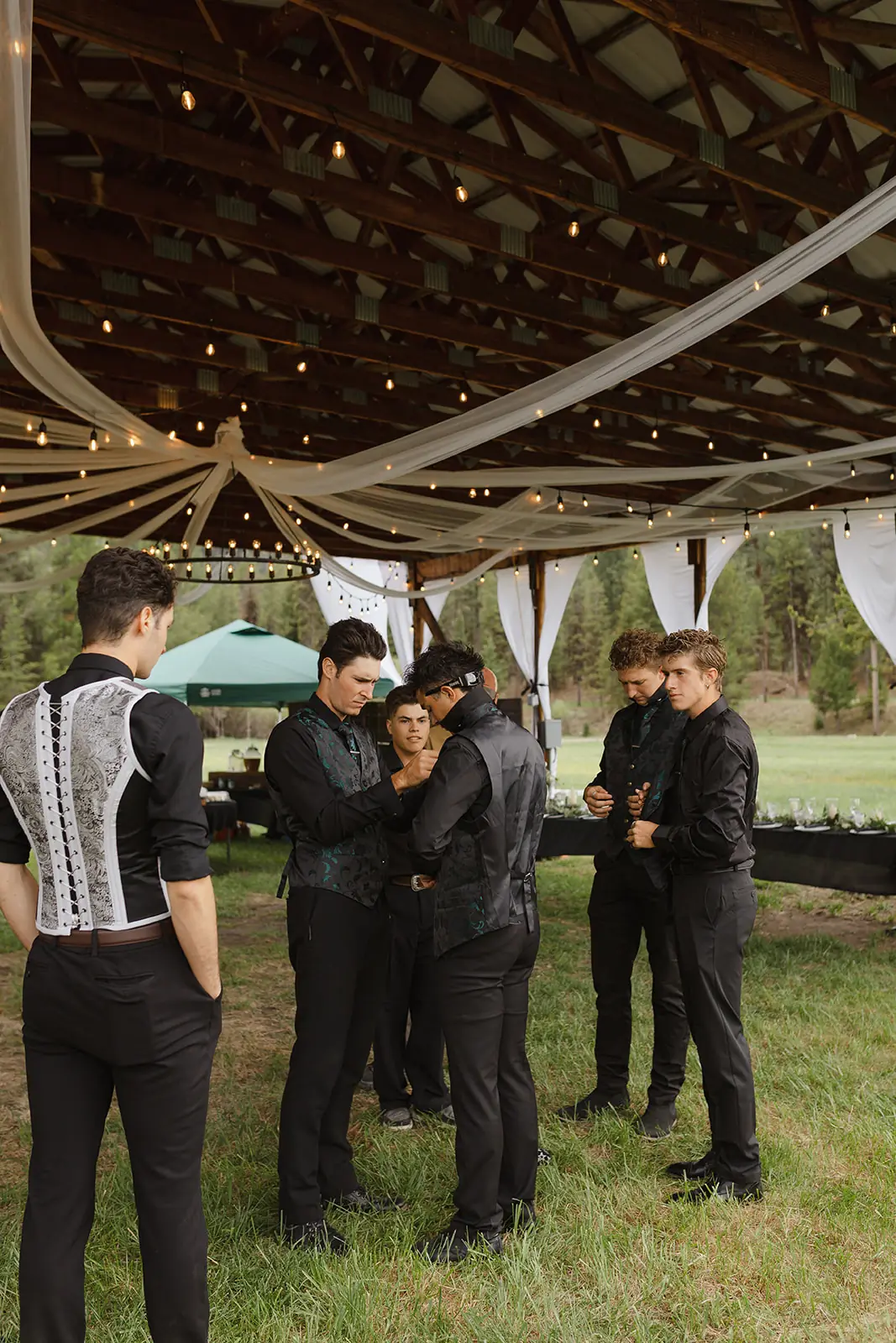 Draped fabric and string lights under the hangar roof, with the groomsmen getting ready below
